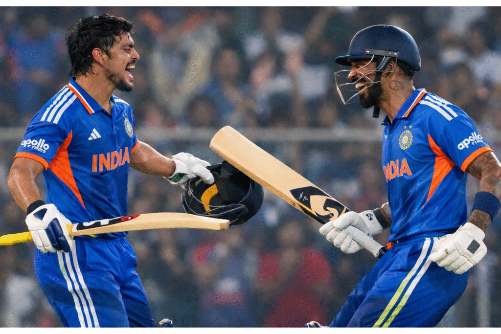 Indian cricket team ke do batsmen blue India jersey mein ground par century ke baad celebration karte hue, haath mein bat aur helmet ke saath.